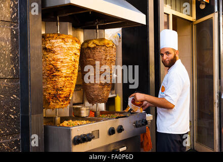 Cuisinier égyptien mâle en face de brochette de poulet et agneau viande shawarma sur un grill, la préparation d'une denrée alimentaire sandwich au Moyen-Orient Banque D'Images