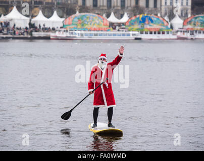 Hambourg, Allemagne. Dec 19, 2015. Un homme habillé en père Noël fait son chemin à travers la rivière Alster sur un paddleboard standup à Hambourg, Allemagne, 19 décembre 2015. Photo : DANIEL BOCKWOLDT/dpa/Alamy Live News Banque D'Images