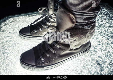 Chaussures de sport, chaussures chaudes debout sur verre fissuré, correction tonale froid, retro style contraste filtre photo Banque D'Images