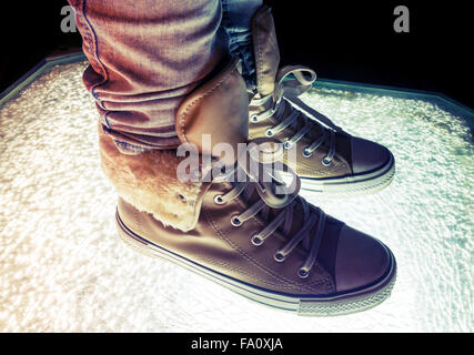 Chaussures de sport, chaussures chaudes debout sur verre fissuré, correction tonale colorés, filtre photo style rétro Banque D'Images
