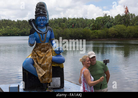 Un couple qui a l'aide d'un bâton selfies selfies en face du dieu hindou Shiva à Ganga Talao - pèlerinage hindou Banque D'Images