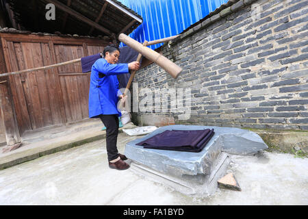 Qiandongnan, province du Guizhou en Chine. Dec 19, 2015. Une femme de l'ethnie Dong bat pour ramollir le tissu tissé à la main dans la région de Paradise Village de Rongjiang Comté, au sud-ouest de la province du Guizhou, en Chine, le 19 décembre 2015. Le tissu artisanal est principalement utilisé par les populations locales pour faire de costumes traditionnels de Dong groupe ethnique. © Wu Jibin/Xinhua/Alamy Live News Banque D'Images