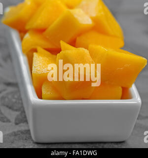 Les dés de mangue en cubes placé et servi sur un plat blanc composition carrée Banque D'Images