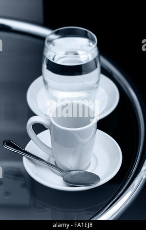 Café Espresso tasse vide et verre d'eau sur la table de chevet closeup Banque D'Images