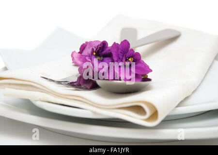 La cuillère à la fourchette sur une serviette et d'une assiette décorée avec des violettes Banque D'Images