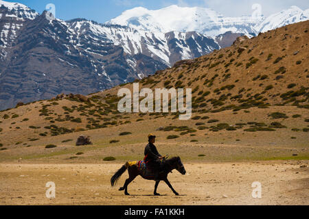 L'homme bouddhiste monte un cheval en pèlerinage trois fois autour d'un lac sacré entre les montagnes de l'Himalaya dans le Spiti Valley Banque D'Images