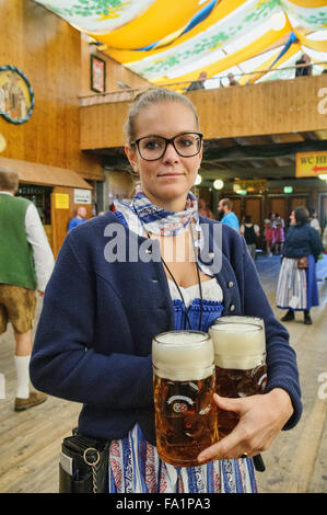 Serveuse dans une tenue traditionnelle portant des lunettes géantes de bières dans l'Oktoberfest à Munich, Allemagne Banque D'Images