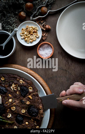 Personne découpe d'une Méditerranée fête la farine de châtaigne Gâteau à plat blanc sur le plateau de table en bois avec des ingrédients et de Noël d Banque D'Images