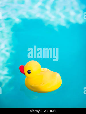 Canard en caoutchouc flottant dans l'eau d'un bleu profond. Banque D'Images