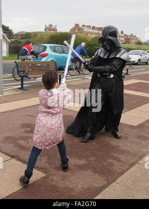 Dark Vador de Star Wars a une bataille sabre de lumière avec un jeune enfant sur le trottoir de la promenade de Southsea, Angleterre Banque D'Images