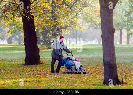 Homme avec deux bébés à dormir dans un landau en automne Hyde Park Londres Angleterre Royaume-Uni Europe Banque D'Images