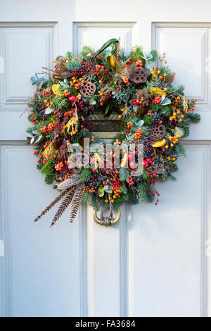 Berry Noël, feuillage, fruits et plumes couronne sur la porte en bois. Arles, France Banque D'Images