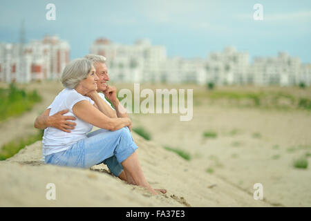 Vieux couple sitting on sand Banque D'Images