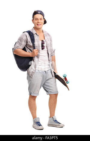 Portrait d'un jeune skater tenant un skateboard et portant un sac à dos bleu isolé sur fond blanc Banque D'Images