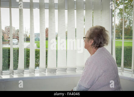 90 ans, femme, et à la fenêtre d'un jour de pluie. UK Banque D'Images