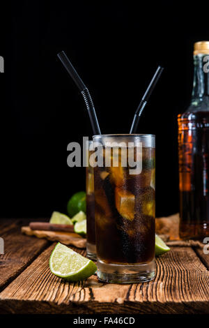 Longdrink Cuba Libre (froid) avec rhum brun et citron vert frais sur fond de bois rustique Banque D'Images