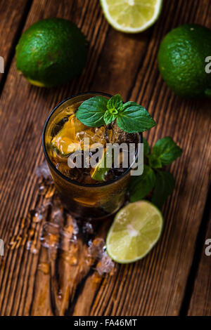 Longdrink Cuba Libre avec des morceaux de glace concassée et de lime sur fond de bois Banque D'Images