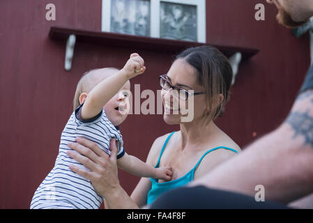 Bébé garçon dans les bras de sa mère offrant de la nourriture à son père, Munich, Bavière, Allemagne Banque D'Images