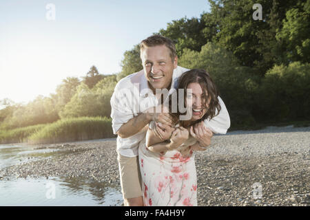 Young woman piggyback ride donnant à son mari, à Lakeside, Bavière, Allemagne Banque D'Images