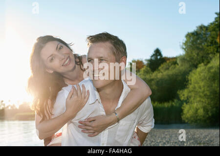 Mature man giving piggyback ride à son épouse à Lakeside, Bavière, Allemagne Banque D'Images