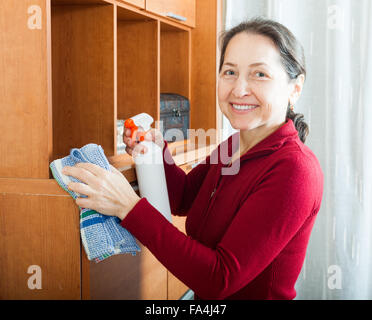 Mature Woman cleaning meubles avec cleanser et rag Banque D'Images