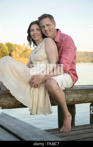 Portrait of mature couple sitting on pier, Bavière, Allemagne Banque D'Images