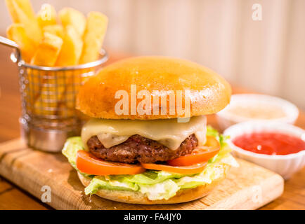 Un hamburger est servi avec de la salade et du fromage sur le dessus Banque D'Images