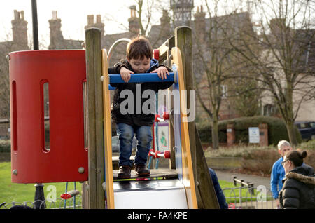 Un jeune garçon joue sur une diapositive dans une aire de jeux. Banque D'Images