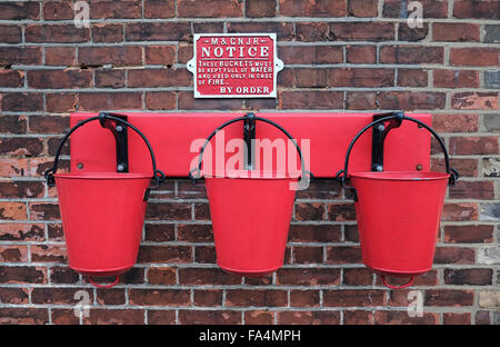 Trois seaux d'incendie rouge accroché sur un mur de briques Banque D'Images
