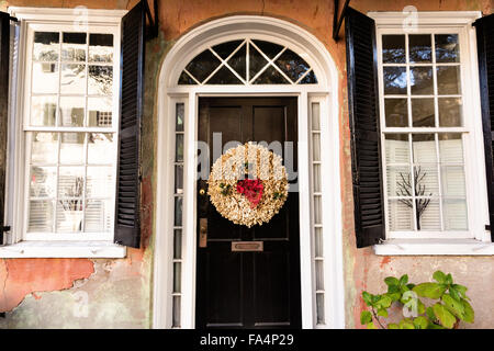 Porte à un accueil traditionnel le long de la rue de l'église décorée d'une couronne de Noël pour la saison de vacances à Charleston, SC. Banque D'Images