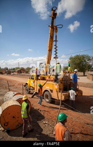 Chaîne de travailleurs nouveaux câbles d'alimentation dans un village rural près de Dodoma, Tanzanie, Afrique de l'Est. Banque D'Images