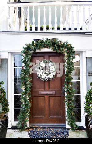 Porte à un accueil traditionnel le long de la rue de l'église décorée d'une couronne de Noël pour la période des fêtes dans le quartier historique de Charleston, SC. Banque D'Images