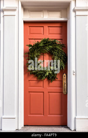 La porte en bois sur une maison traditionnelle le long de la rue de l'église décorée d'une couronne de Noël pour la période des fêtes dans le quartier historique de Charleston, SC. Banque D'Images