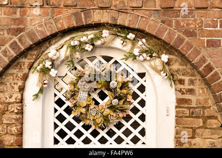 La porte en bois sur une maison traditionnelle le long de la rue de l'église décorée d'une couronne de Noël pour la période des fêtes dans le quartier historique de Charleston, SC. Banque D'Images