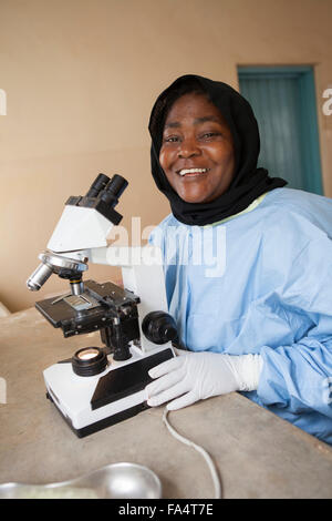 Assistant de laboratoire fonctionne un microscope à un centre de santé fonctionnant à l'énergie solaire dans la région de Kigoma, l'ouest de la Tanzanie. Banque D'Images