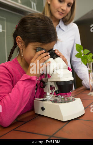 Écolière avec professeur regardant au microscope, Fürstenfeldbruck, Bavière, Allemagne Banque D'Images