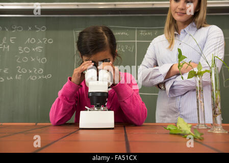 Écolière avec professeur regardant au microscope, Fürstenfeldbruck, Bavière, Allemagne Banque D'Images