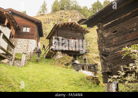 Vue arrière des deux randonneurs mature en passant par les chalets, alpes autrichiennes, Carinthie, Autriche Banque D'Images