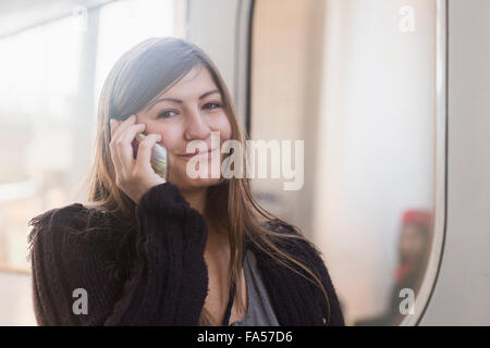 Portrait of a young woman talking on mobile phone devant un train, Freiburg im Breisgau, Bade-Wurtemberg, Allemagne Banque D'Images