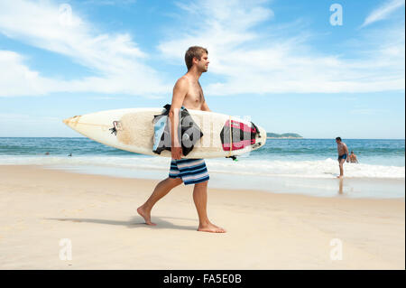 RIO DE JANEIRO, Brésil - le 29 mars 2014 : surfer brésilien promenades avec surf le long du rivage de la plage d'Ipanema. Banque D'Images