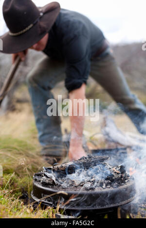 De l'argile Baird Bogong Aventures prépare le dîner sur le feu de camp dans la Bogong High Plains. Banque D'Images