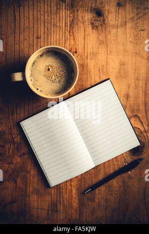 Vue de dessus de l'ordinateur portable ouvert avec des pages blanches, l'écriture crayon et tasse de café sur le vieux bureau en bois, tons rétro droit Banque D'Images