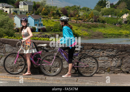 Cyclisme en Irlande.et deux jeunes touristes féminins au pont de Killorglin au-dessus de la rivière Laune, comté de Kerry, Irlande. Banque D'Images