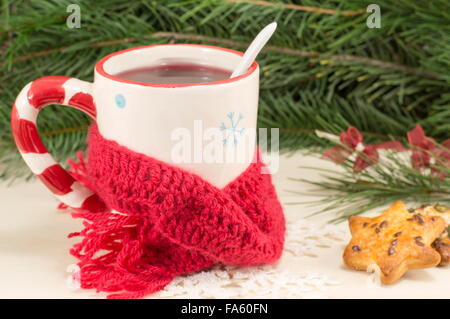 Tasse de thé de Noël couverts par l'écharpe d'hiver avec sapin en arrière-plan Banque D'Images