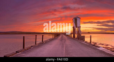 La chaussée à l'Île Sainte photographiés avec un spectaculaire coucher de soleil. À marée haute la chaussée est infranchissable, refuge des cabanes de stil Banque D'Images