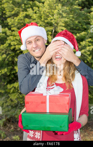 Garçon étonnant une fille avec un cadeau de Noël en plein air Banque D'Images