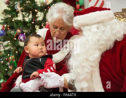 Le Père Noël est assis avec Mrs Claus et de l'Alaska Native d'un enfant au cours d'une visite dans les villages éloignés dans le cadre de l'Opération Père Noël 5 décembre 2015 à Saint Mary's, de l'Alaska. Le programme a été organisé pour 59 ans et apporte de Noël aux groupes mal desservis, les villages éloignés à travers l'Alaska. Banque D'Images