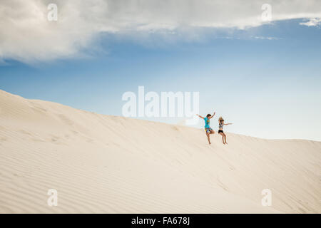 Garçon et fille sautant dans les dunes de sable, tête verte, Australie occidentale, Australie Banque D'Images