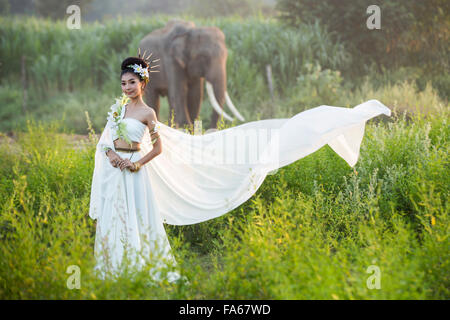 Femme en robe blanche, debout devant un éléphant, Thaïlande Banque D'Images