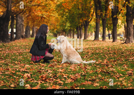 Girl sitting in park with her dog Banque D'Images